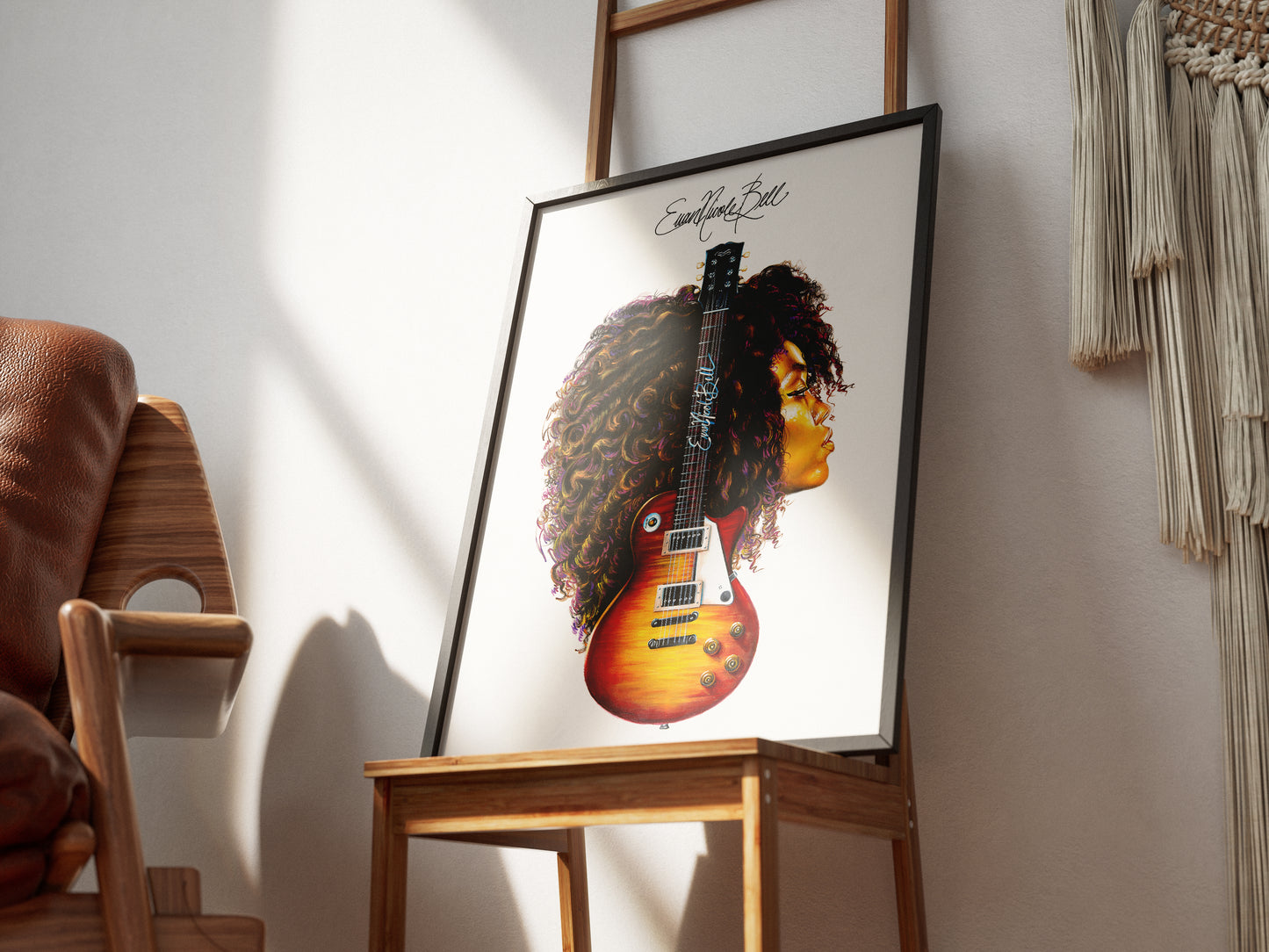 Evan Nicole Bell print in black frame and dramatic lighting. Frame is placed on wooden chair.