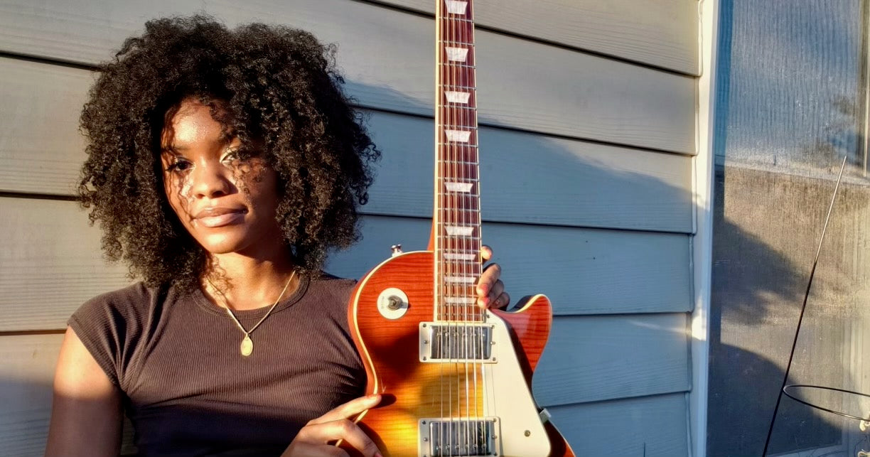 Baltimore, Maryland musician Evan Nicole Bell poses outside with her Epiphone Les Paul guitar.