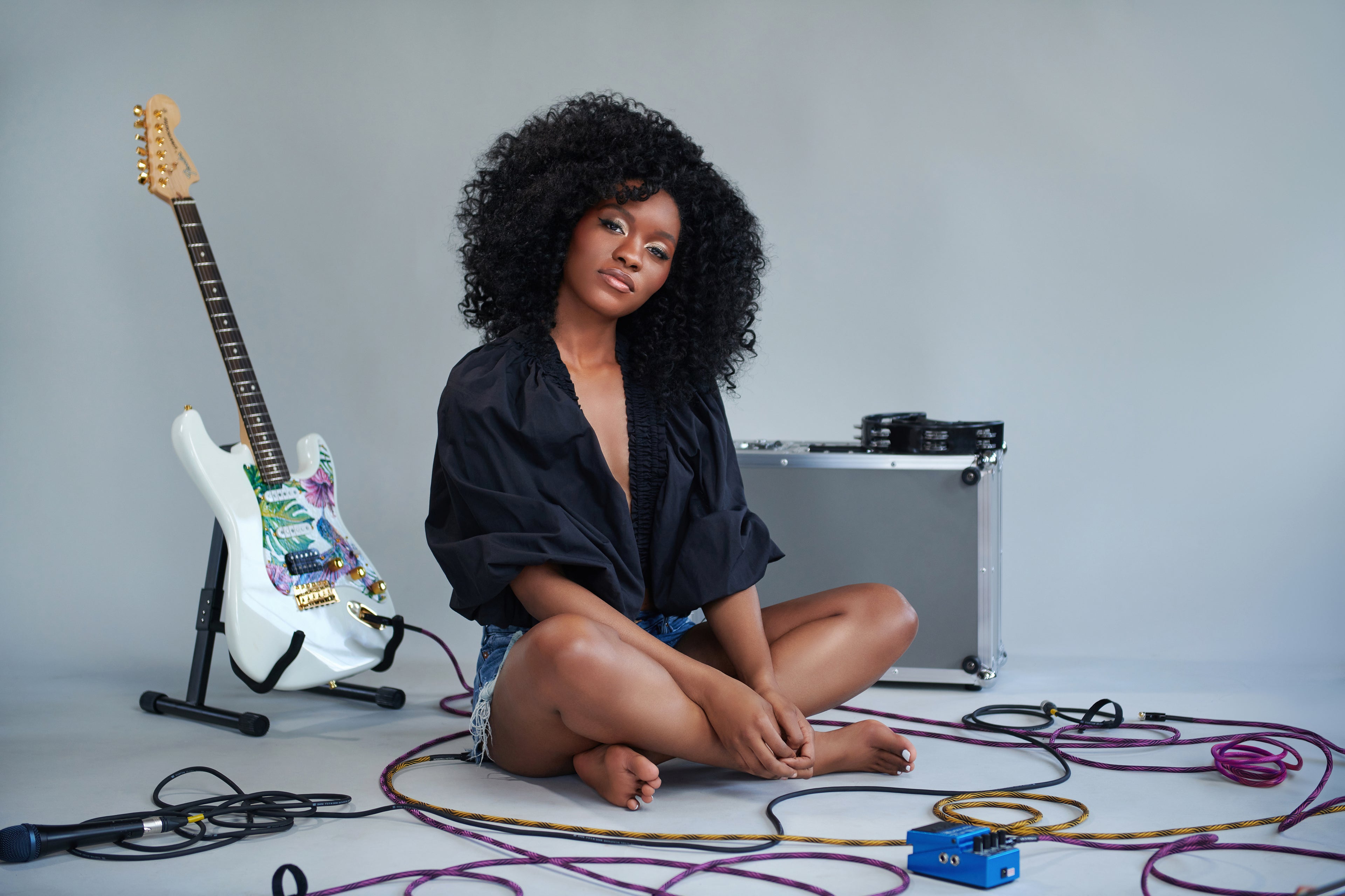 Evan Nicole Bell sitting on floor with electric guitar and guitar cables